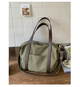 Détail du sac fourre-tout en toile olive avec anses en cuir marron et poche avant spacieuse