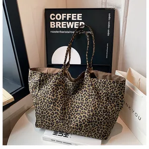 Top view of a large leopard print tote bag with brown lining on a white table