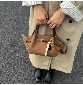 Close-up of brown suede tote bag featuring leather handles and decorative wood beads