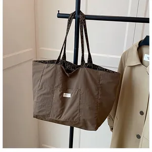 Detail of brown tote bag featuring leopard print straps and a front patch pocket design