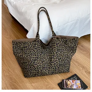 Macro shot of large leopard print tote bag on floor with lifestyle props for scale