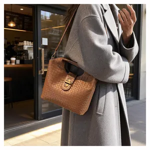 Dettaglio della trama in pelle intrecciata marrone e chiusura in bronzo di una borsa chic