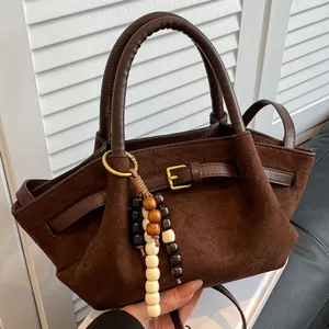 Vintage dark brown matte handbag with wooden beads and gold buckle on wooden background