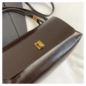 Dettaglio borsa vintage marrone scuro con chiusura metallica quadrata in oro