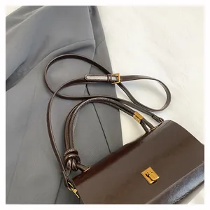Dettaglio borsa in pelle marrone vintage con chiusura dorata e manico annodato chic