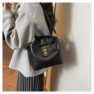 Dettaglio della borsa a mano in pelle intrecciata nera con chiusura in metallo oro