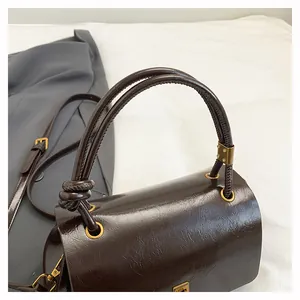 Dettaglio borsa in pelle verniciata testa di moro con finiture metalliche dorate lucide