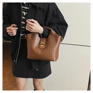 Dettaglio borsa a mano marrone intrecciata con chiusura a scatto dorata e texture in pelle