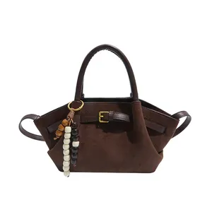 Retro brown frosted suede handbag with wooden bead charm and round handles on white background