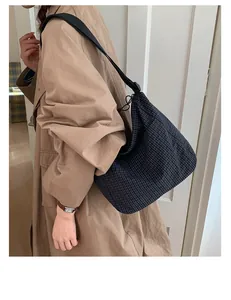 Dettaglio della borsa a tracolla in tela scozzese blu navy con coulisse su modella in trench