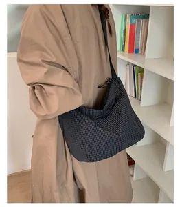 Dettaglio della borsa a tracolla a quadretti neri con coulisse su modella in trench kaki