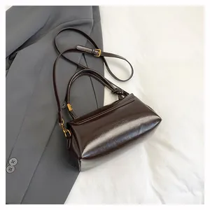 Dettaglio della borsa in pelle verniciata marrone con finiture in oro e nodo