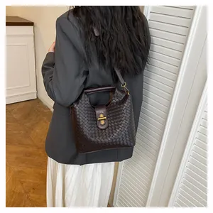 Borsa a mano intrecciata marrone scuro con fibbia dorata indossata a tracolla dalla modella