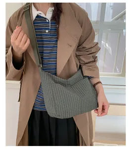 Dettaglio borsa a tracolla in tela a quadri verdi con ampia tracolla regolabile in nylon