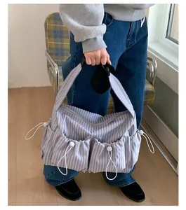 Dettaglio borsa in nylon a quadri viola con tasche a coulisse e tracolla regolabile larga