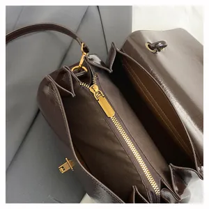 Dettaglio interno della borsa in pelle lucida marrone con scomparto a zip e finiture dorate