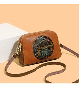 Close-up of vintage brown leather bag with dual zippers and ornate elephant metal relief