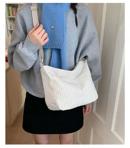 Dettaglio di una borsa a tracolla in tela a righe indossata da una modella in stile casual