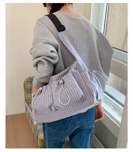 Dettaglio laterale della borsa in nylon a righe con tasche regolabili con coulisse