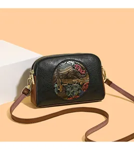 Detail of vintage crossbody bag with elephant relief and dual-layer zipper texture