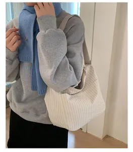 Dettaglio della borsa tote in tela a righe beige con tracolla larga a forma di mezzaluna