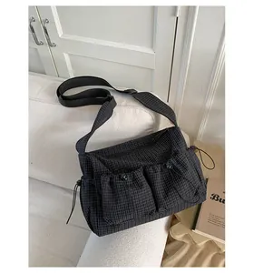 Dettaglio della borsa a tracolla in nylon a quadretti con tasche a coulisse e ampia tracolla