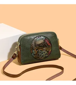 Macro detail of retro green leather bag with embossed elephant pattern and double gold zippers