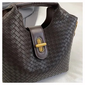 Dettaglio di una borsa tote in pelle intrecciata con chiusura a scatto dorata e texture