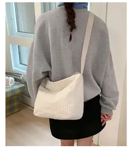 Dettaglio della trama della borsa a tracolla a righe beige indossata da una modella
