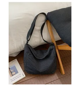 Dettaglio borsa a tracolla a quadretti neri con ampia tracolla in nylon e cerniera