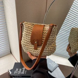 Détail du sac seau en paille tressée avec rabat en cuir marron et boucle en métal rétro