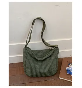 Dettaglio della borsa hobo a quadretti verdi con tracolla regolabile su legno