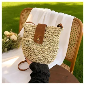 Detailed view of woven straw crossbody bag with brown leather flap and retro bronze buckle