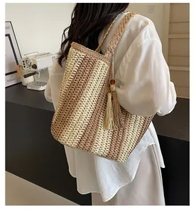 Dettaglio della borsa tote in paglia a righe intrecciata a mano con nappe decorative