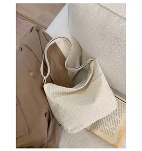 Dettaglio borsa in tela a quadretti beige con ampia tracolla e tasca laterale su divano
