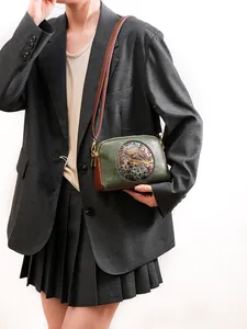 Detail of vintage crossbody bag with ethnic elephant emblem on high-quality leather