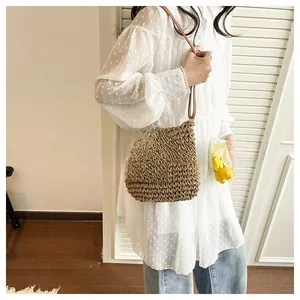 Detailed texture of brown woven straw crossbody bag with faux leather strap and buckle