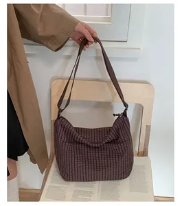 Dettaglio di borsa hobo in tela a scacchi marrone con tracolla in un ambiente retrò