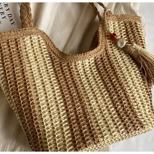 Dettaglio macro della borsa tote in paglia intrecciata a mano con nappe di perline decorative