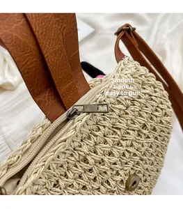 Détail de la fermeture éclair en bronze et du tissage sur le sac de plage en paille beige