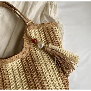 Dettaglio ravvicinato di una borsa tote in paglia con nappe e trama intrecciata a contrasto