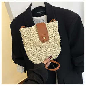 Detail of woven straw crossbody bag with brown leather flap and golden buckle