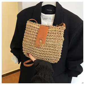 Detail of woven straw crossbody bag with brown leather flap and golden buckle