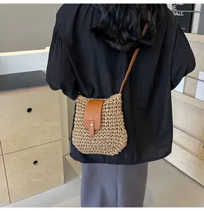 Détail du sac bandoulière en paille avec rabat en cuir marron et boucle à rivets en laiton