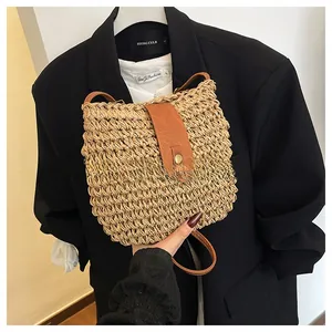 Detail of hand-woven straw crossbody bag featuring brown leather flap and brass buckle