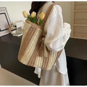 Dettaglio di una borsa tote grande in paglia con trama a righe e nappa vista sul modello