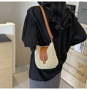 Détail d'un sac bandoulière en paille avec rabat en cuir marron et sangle réglable
