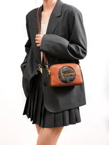 Brown vintage crossbody bag with artistic round pattern shown on a fashion model