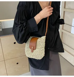 Détail du sac bandoulière en paille tissée avec rabat en cuir brun et bouton pression