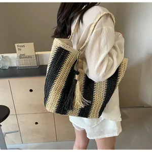 Dettaglio della borsa tote in paglia intrecciata a righe nero e beige con nappe